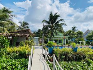 a walkway in front of a house with palm trees at NAI Homestay in Ben Tre
