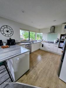 a large kitchen with a large clock on the wall at Welcomebay Haven in Tauranga