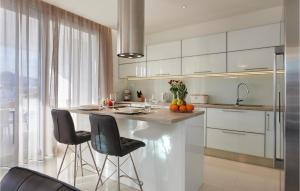a kitchen with white cabinets and a island with bar stools at Amazing Home In Trogir With Sauna in Trogir