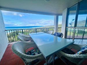 a table and chairs on a balcony with the ocean at Whalewatch Ocean Beach Resort in Point Lookout