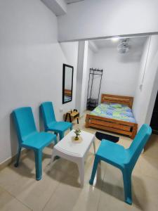 a bedroom with blue chairs and a bed and a table at Refugio Del Mar in Burrero