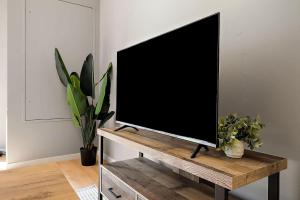 a television on a wooden stand in a room with plants at CozySuites Mill District with pool gym #12 in Minneapolis