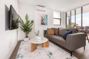 a living room with a couch and a table at Azure Apartments Bondi by Urban Rest in Sydney