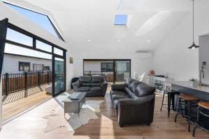 Una sala de estar con dos sofás y una cocina. en The Sun Trap - Waihi Beach Holiday Home, en Waihi Beach