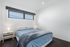 Un dormitorio blanco con una cama y una ventana. en The Sun Trap - Waihi Beach Holiday Home, en Waihi Beach
