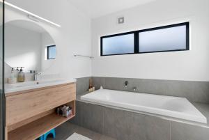 una bañera en un baño con ventana en The Sun Trap - Waihi Beach Holiday Home, en Waihi Beach 18 fotos más