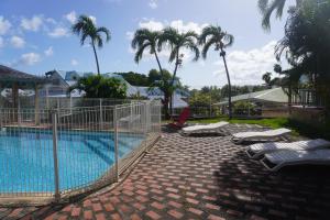 a swimming pool with lounge chairs and palm trees at APPARTEMENT CAMELIA 2 avec PISCINE et à 3 min de la PLAGE Pointe Marin in Sainte-Anne +3 photos