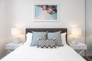 a bedroom with a white bed with two night stands at Azure Apartments Bondi by Urban Rest in Sydney