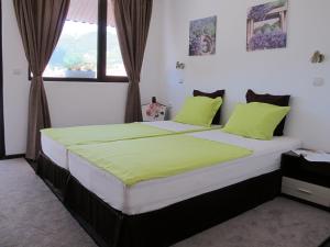 a bedroom with a large bed with green pillows at Guest House & Bistro Lefterova in Kotel