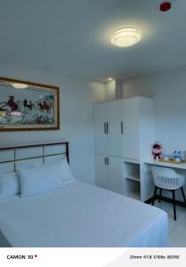 um quarto com uma cama branca e uma escrivaninha em EPM Tower Hotel and Events Place em Sampong