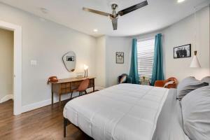 a white bedroom with a bed and a desk at Massive Mid-Century Marvel 5 Bedrooms and Parking in Washington +28 photos