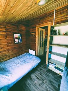 Un dormitorio con una cama en una cabaña de madera. en VerLema House 46, en Augustów