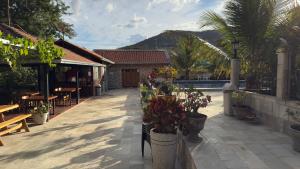 a patio with tables and potted plants and a building at Pousada de Campo Estância Bahamas in Pirenópolis