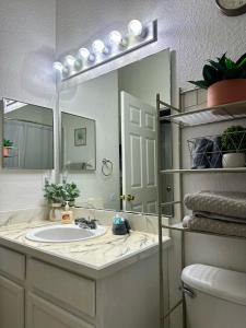 ein Badezimmer mit Waschbecken und großem Spiegel in der Unterkunft Cozy 3 bedroom Condo near Disney World! in Kissimmee
