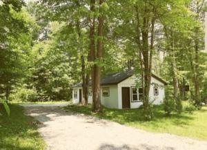 a small white house in the middle of trees at The Reel Freedom Cottage at Leesville Lake in Carrollton