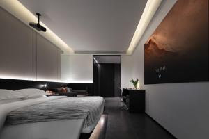 a bedroom with a bed and a desk and a painting at Enji M Hotel-Chongqing Shapingba High-speed Railway Station Three Gorges Square in Chongqing