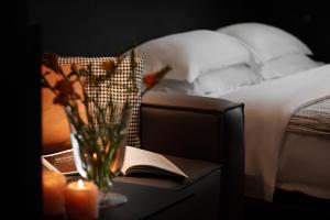 a vase of flowers on a table next to a bed at Enji M Hotel-Chongqing Shapingba High-speed Railway Station Three Gorges Square in Chongqing