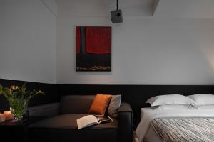 a bedroom with a bed and a couch with a book at Enji M Hotel-Chongqing Shapingba High-speed Railway Station Three Gorges Square in Chongqing