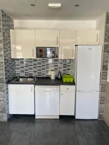 kuchnia z białymi szafkami i białą lodówką w obiekcie Hego Haize Zarautz Hostel w mieście Zarautz