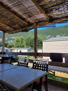 une table et des chaises sous une pergola en bois dans l'établissement Camping Le Hameau Des Pécheurs, à Novalaise