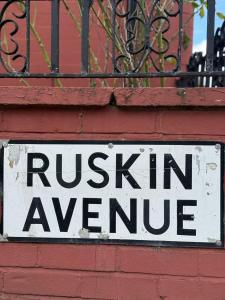 a white sign on a red brick wall at Britlodge Ruskin Ave Home in Manchester