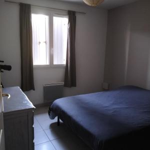 Un dormitorio con una cama azul y una ventana. en L infiniment zen, en Caromb