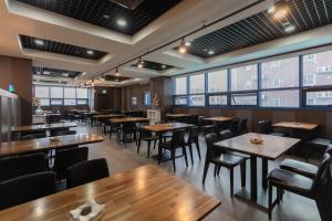 a restaurant with wooden tables and chairs and large windows at With Stay Jeju Hotel in Jeju