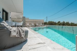 a swimming pool with a couch sitting on a patio at Zandore Villas Perdika private Luxury Villas Epirus Villas in Pérdika