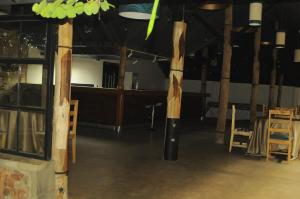 a room with wooden poles and chairs and a table at Cocopark Hotel in Rwinkwavu
