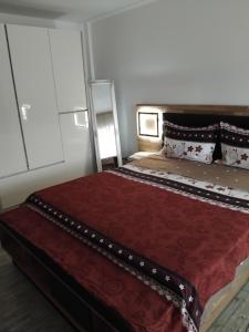 a bedroom with a large bed with a red comforter at Manu Apartament in Târgu Neamț