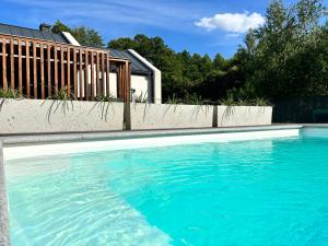 a swimming pool with blue water in front of a house at Leśna Polana Domki in Okuninka