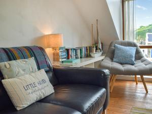 a living room with a leather couch and a chair at The Boathouse in Little Haven
