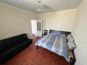 a bedroom with a bed and a black couch at Домик у моря in Ömirzaq