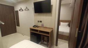 um quarto com uma secretária, uma cama e uma televisão em WE Hotel Kowloon em Hong Kong