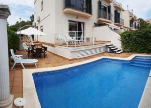 a villa with a swimming pool in front of a house at Casa Garcia in Sitges