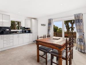 una cocina con armarios blancos y una mesa y sillas de madera. en Seaborne Cottage - Pwlheli, en Pwllheli 25 fotos más
