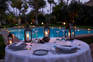 a table with a white table cloth with candles and lights at Dar Ayniwen Garden Hotel & Bird Zoo in Marrakesh