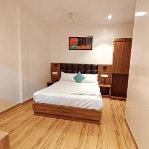 a bedroom with a bed with white sheets and wooden floors at Deluxe Residency Nr- Mumbai International Airport in Mumbai