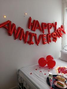 Un cartel rojo de feliz aniversario en una pared blanca en Ereens homestay 3 bedroom apartment, en Brinchang 31 fotos más