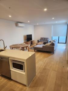 a kitchen and living room with a couch and a table at Modern Apartment Airport Area in Melbourne