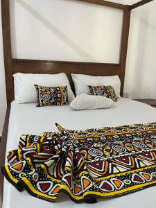a bed with a colorful blanket and pillows on it at Reef Nungwi House in Nungwi +56 photos