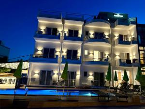 a white building with a swimming pool in front of it at Galaxy Hotel in Ksamil