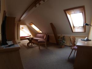 a attic room with a couch and a table and windows at Gasthof zur Schweiz in Jena