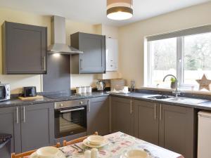 a kitchen with gray cabinets and a table and a window at Two Dorchester Drive - Uk32036 in Inglewhite