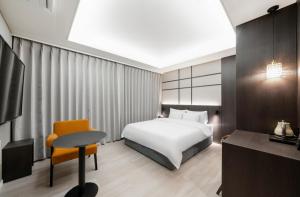 una camera da letto con un letto, un tavolo e una scrivania di Hotel Lantana Sangmu a Gwangju