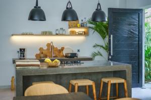 a kitchen with a large counter with stools at Stylish 2bedroom Villa Canggu Padonan in Kerobokan
