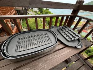 a large metal grill sitting on a wooden bench at Log House Namioto -ログハウス波音- in Ōbiki
