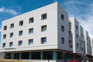 een wit gebouw met een auto ervoor geparkeerd bij Days Inn by Wyndham Minatitlan in Minatitlán