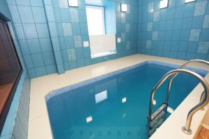 a blue tiled bathroom with a swimming pool at Gubernia in Kharkiv