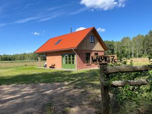 a small house with an orange roof and a fence at Wiluki Nasz Dom in Wiluki